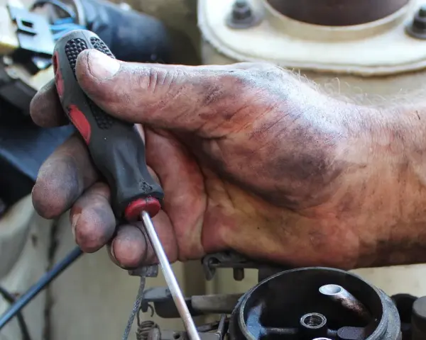 Brudna ręka mechanika z kluczem, naprawia coś w samochodzie. Może to być związane z linki skrzyni biegów objawy.