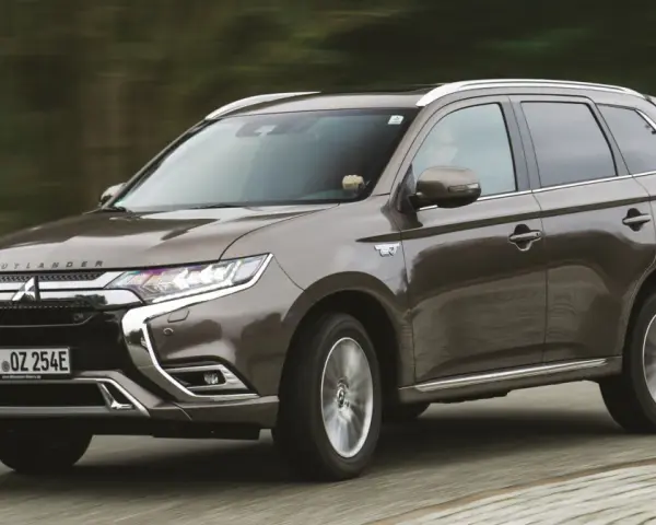 Brązowy Mitsubishi Outlander PHEV jedzie po drodze, zamazane tło sugeruje ruch.