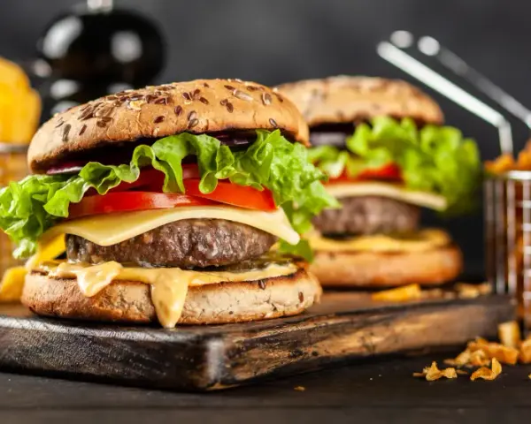 Dwa soczyste hamburgery z serem, sałatą i pomidorem, podane z frytkami.