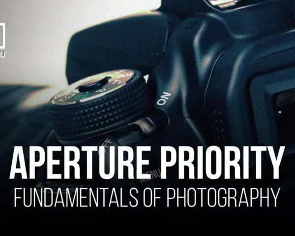 Gros plan sur un appareil photo, avec le texte "APERTURE PRIORITY" et "FUNDAMENTALS OF PHOTOGRAPHY". Le mode priorité ouverture est essentiel pour maîtriser la profondeur de champ.