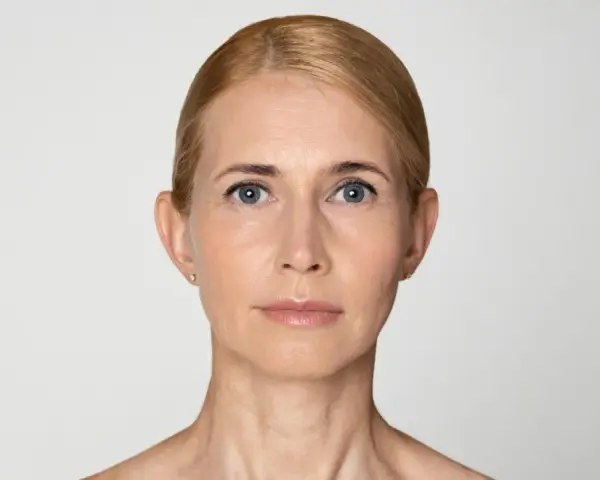 Naturalna twarz 40-latki z widocznymi oznakami czasu, ale pełna wdzięku.