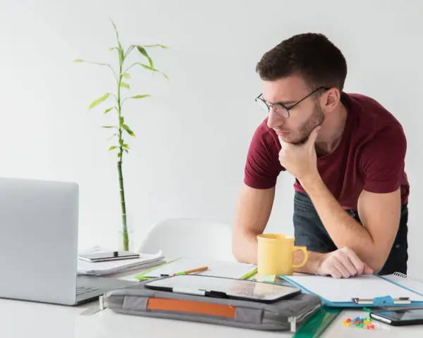 Joven autónomo reflexiona en su escritorio. Lo cotizado como autónomo cuenta para el paro, una tranquilidad para su futuro.