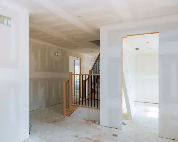 Interni in fase di finitura, con pareti pronte per essere rivestite con cartongesso senza telaio. Scala in legno e metallo.