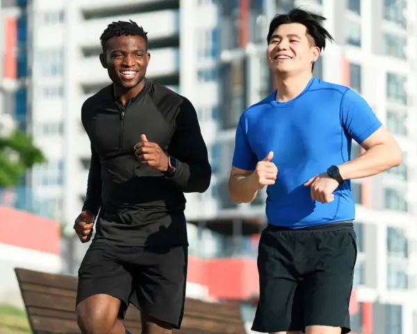 Deux hommes souriants courent ensemble dans un parc, profitant de leur routine pour courir tous les jours.