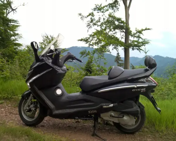 Czarny skuter Sym GTS 125 na górskiej drodze. Jego prędkość maksymalna pozwala na odkrywanie malowniczych zakątków.