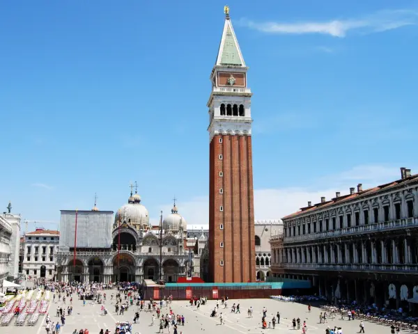 La maestosa altezza del campanile di San Marco domina Piazza San Marco, con la Basilica sullo sfondo e la folla che passeggia.