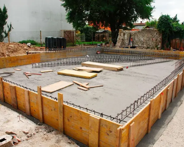 Drewniane szalunki i zbrojenie czekają na beton, tworząc fundamenty z kamienia.