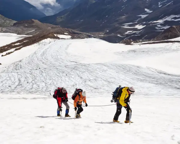 Drei Bergsteiger seilen sich über einen eisigen Gletscher in den Alpen ab.