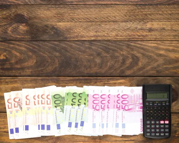 Banknoty euro i kalkulator na drewnianym tle.