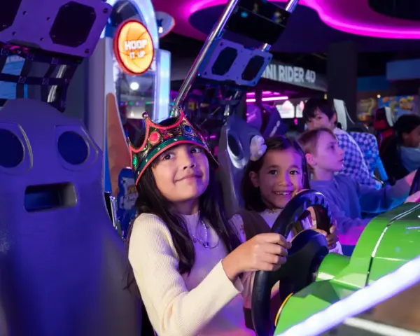 Kinder mit Kronen auf dem Kopf spielen in einer Spielhalle in Berlin Rennspiele.