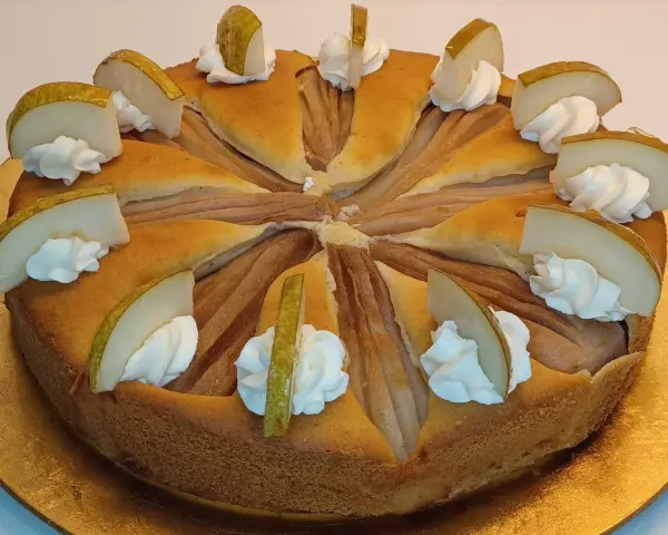 Ein köstlicher Birnenkuchen, verziert mit Sahnetupfern und frischen Birnenspalten. Perfekt für ein Birnenkuchen Rezept.
