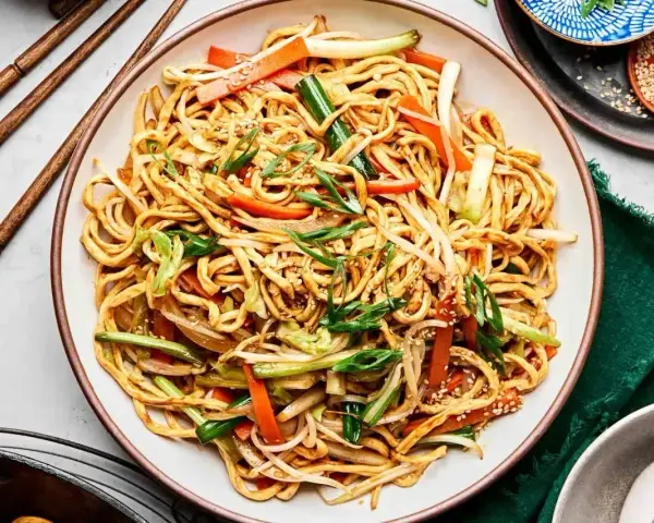 Pyszny makaron chow mein z warzywami i sezamem, gotowy do jedzenia pałeczkami.