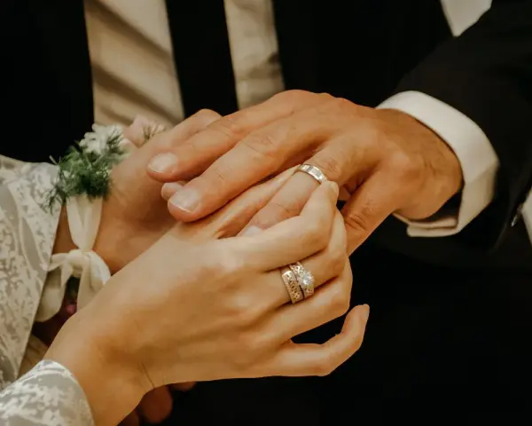 Dłoń panny młodej zakłada obrączkę na palec pana młodego. To ważny moment, jak pytania przed ślubem, symbolizujący miłość i przyszłość.