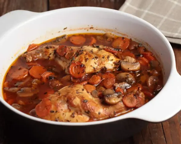 Conejo en cazuela con zanahorias y champiñones en salsa roja.