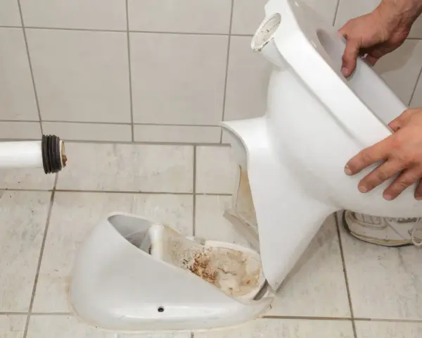 Démontage d'une cuvette de toilettes cassée. Il est temps de changer les toilettes.