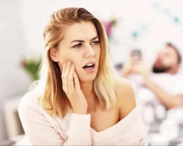 Kobieta z odrętwiałą twarzą po wizycie u dentysty.