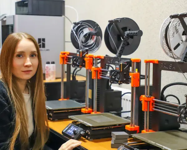 Kobieta w laboratorium obok rzędu drukarek 3D, które są kluczowe dla historii drukarki 3d.