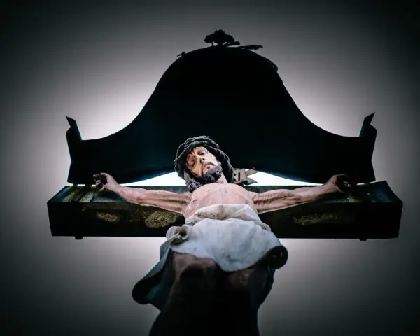 A statue of Jesus on the cross, with a dark canopy above. This image evokes the sacrifice and the question of why Jesus died.