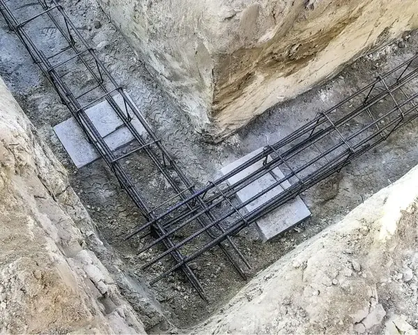 Zbrojenie płyty fundamentowej w wykopie. Stalowe pręty tworzą siatkę, gotową na zalanie betonem.