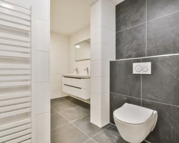 Salle de bain moderne avec wc suspendu, carrelage gris anthracite et blanc, lavabo suspendu et radiateur blanc.