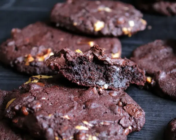 Schokoladenkekse mit Nüssen, die an das subway cookies rezept erinnern. Ein Keks ist zerbrochen und zeigt die saftige Innenseite.