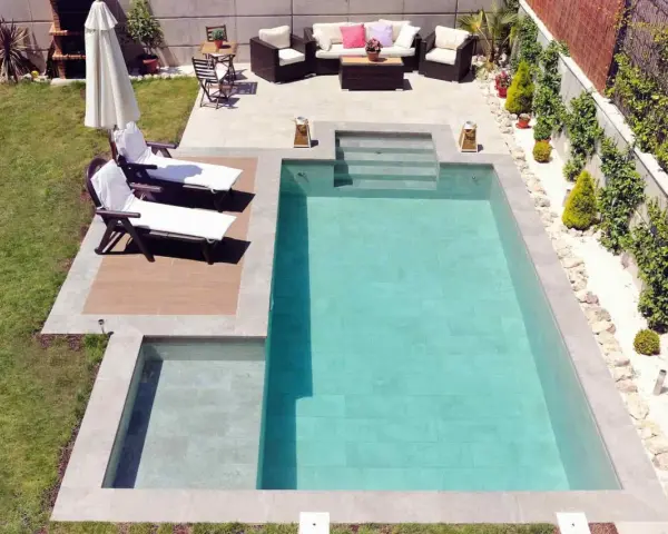 Un jardín con piscinas modernas, tumbonas, zona de estar y barbacoa.