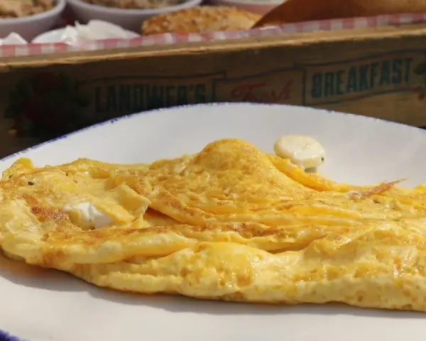 Tortilla francesa dorada en plato blanco, con un toque de queso. ¡Cuidado, la tortilla francesa engorda si no la acompañas con ensalada!