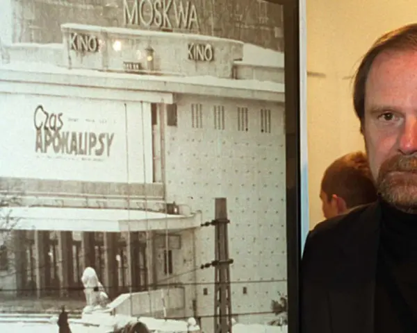 Mężczyzna z brodą obok plakatu kina "Moskwa" z napisem "Czas Apokalipsy".