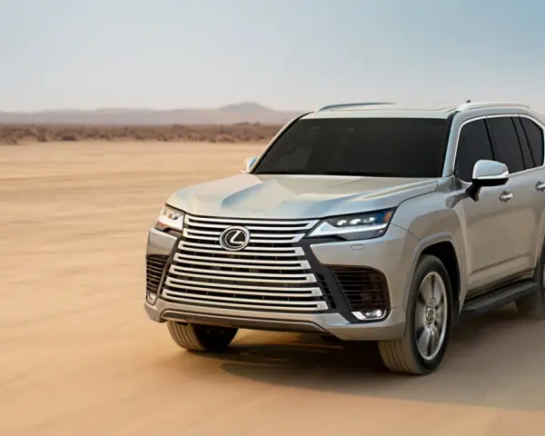 Srebrny Lexus LX 600 przemierza pustynię, zostawiając ślady na piasku.