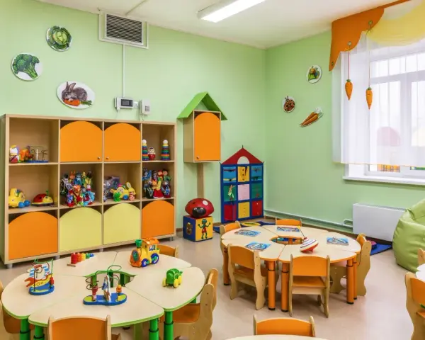 Kolorowa sala przedszkolna z zabawkami i stolikami. Zastanawiasz się, ile kosztuje żłobek? To miejsce wygląda na przyjazne dla dzieci.