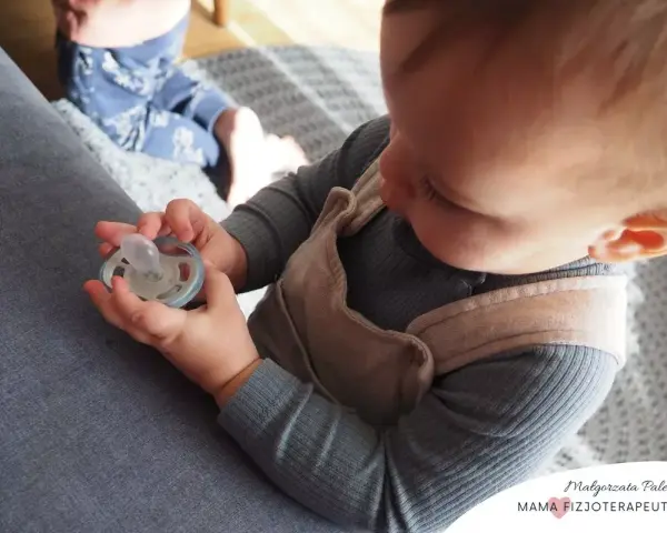 Dziecko trzyma smoczek, zastanawiając się, jak odzwyczaić dziecko od smoczka. Czas na zmiany!