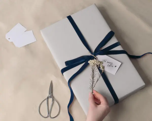 Prezent na 8 rocznicę ślubu, owinięty w szary papier i ozdobiony granatową aksamitną wstążką. Drobna gałązka i karteczka "To my love" dodają uroku.