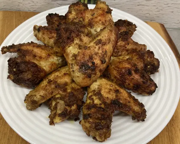 Chrupiące skrzydełka z airfryer ułożone na białym talerzu, apetycznie przypieczone i gotowe do podania.