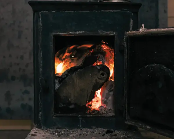 Poêle à bois avec porte ouverte et flammes vives dans le foyer.