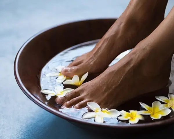 Relaxing foot bath with frangipani flowers. The amount of epsom salt in a foot bath can vary, but a common recommendation is 1/2 cup per gallon of water for a soothing soak.