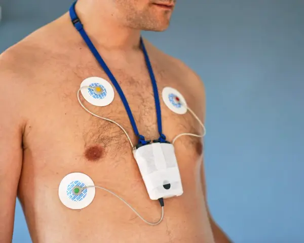 Mężczyzna z elektrodami EKG na klatce piersiowej i urządzeniem do badania holtera. Unikaj wysiłku fizycznego podczas badania holtera.