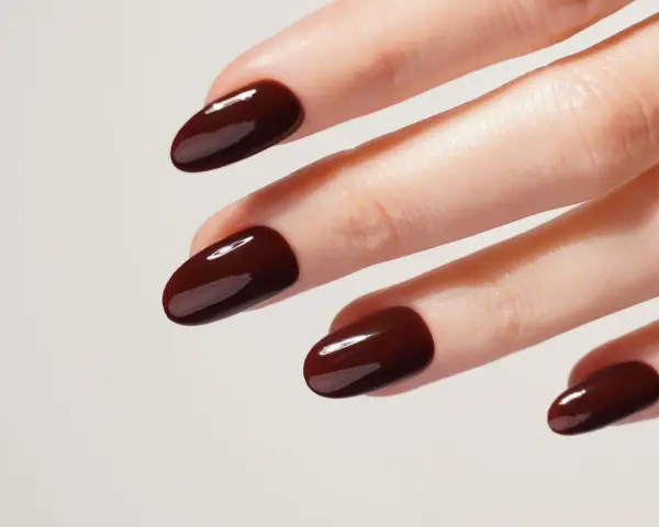 Mani curate con unghie laccate di un intenso color **baby boomer marrone**, lucide e perfette.