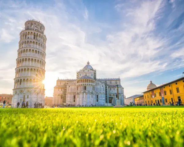 Torre di Pisa e Duomo, tra i più bei posti da visitare in Toscana, con un prato verde brillante e cielo azzurro.