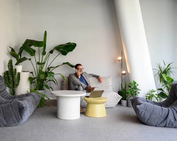 Un homme d'affaires au téléphone dans un coin salon moderne avec des plantes, une idée pour optimiser petit espace.