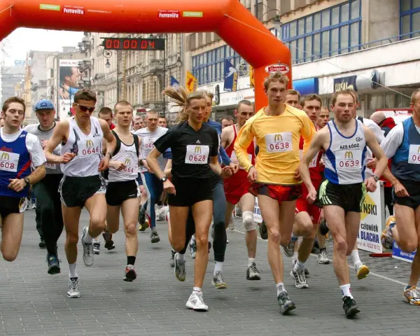 Löpare i en maratonlopp, många med nummerbrickor. En kvinna springer i mitten.