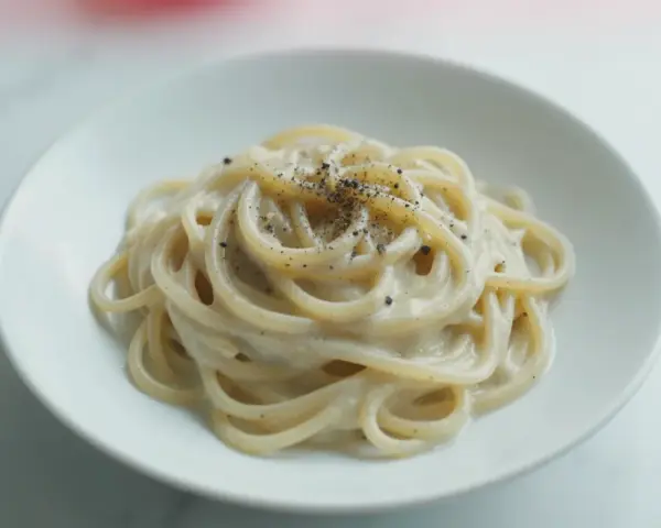Pyszny makaron z pieprzem, kremowy sos otula złociste spaghetti, posypane świeżo mielonym pieprzem.