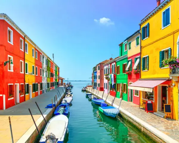 Coloratissima isola a Venezia, con case vivaci affacciate su un canale pieno di barche.