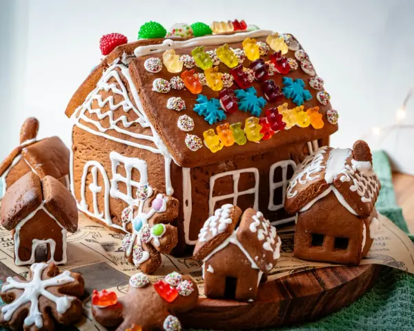 Kreative Ideen für ein Lebkuchenhaus: Ein detailreiches Lebkuchenhaus mit bunten Gummibärchen und kleinen Lebkuchenhäusern drumherum.