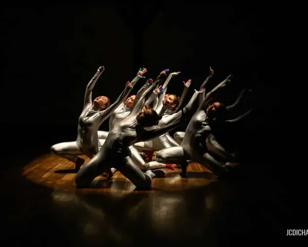 Un groupe de danseurs en costumes argentés, mains levées, dans un photo spectacle captivant.