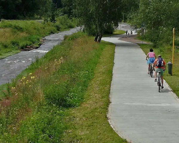 Rowerzyści cieszą się malowniczymi trasami rowerowymi w Muszynie, jadąc wzdłuż rzeki.