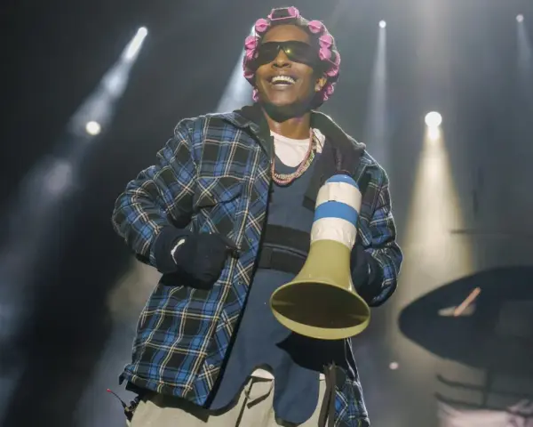 A$AP Rocky na koncercie w kręconych włosach i kratowanej koszuli, trzymający megafon.