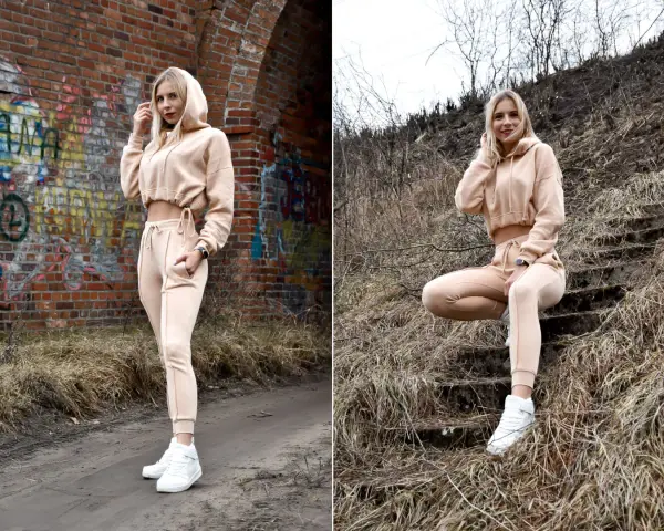Dresy damskie szerokie w beżowym kolorze, idealne na co dzień. Modelka prezentuje je na tle ceglanej ściany i schodów.