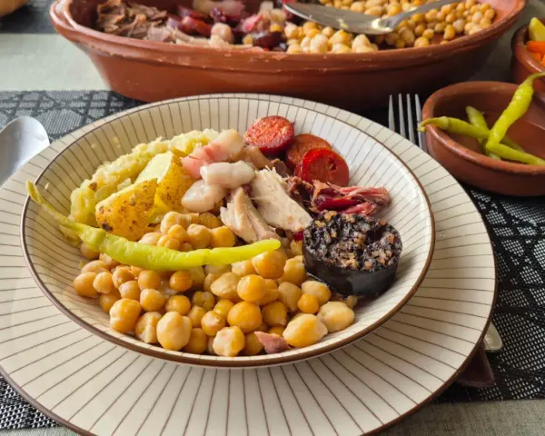 Plato de cocido con garbanzos, patatas, chorizo, morcilla y pimientos.