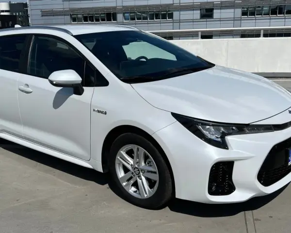 Biały Suzuki Swace Hybrid na parkingu. Elegancki kombi z nowoczesnym designem, gotowy na każdą podróż.