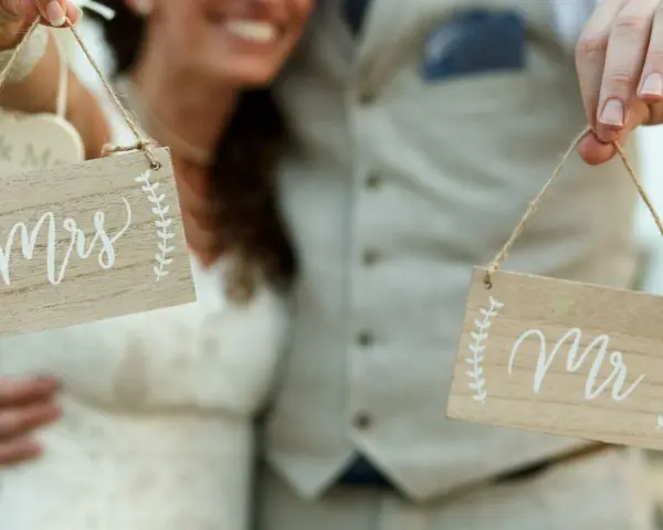 Szczęśliwa para świętuje zmianę nazwiska po ślubie, trzymając tabliczki "Mrs" i "Mr".